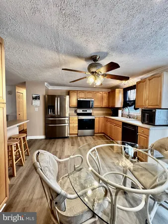 a kitchen with stainless steel appliances kitchen island granite countertop a refrigerator a stove top oven a sink with island and chairs