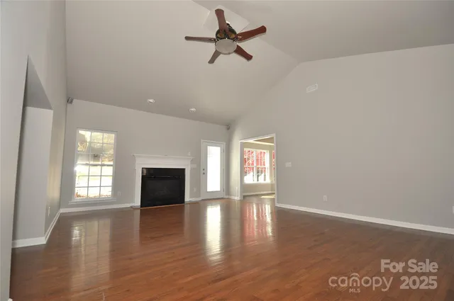 an empty room with ceiling fan and windows