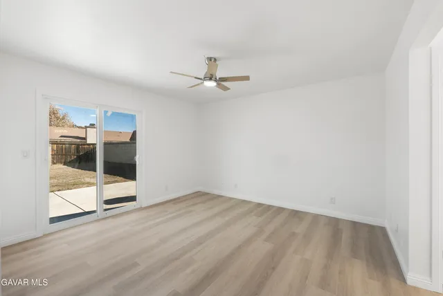 an empty room with wooden floor and ceiling fan