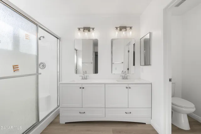 a bathroom with double vanity sink a mirror and a shower