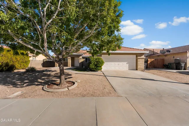 a view of a white house with a large tree