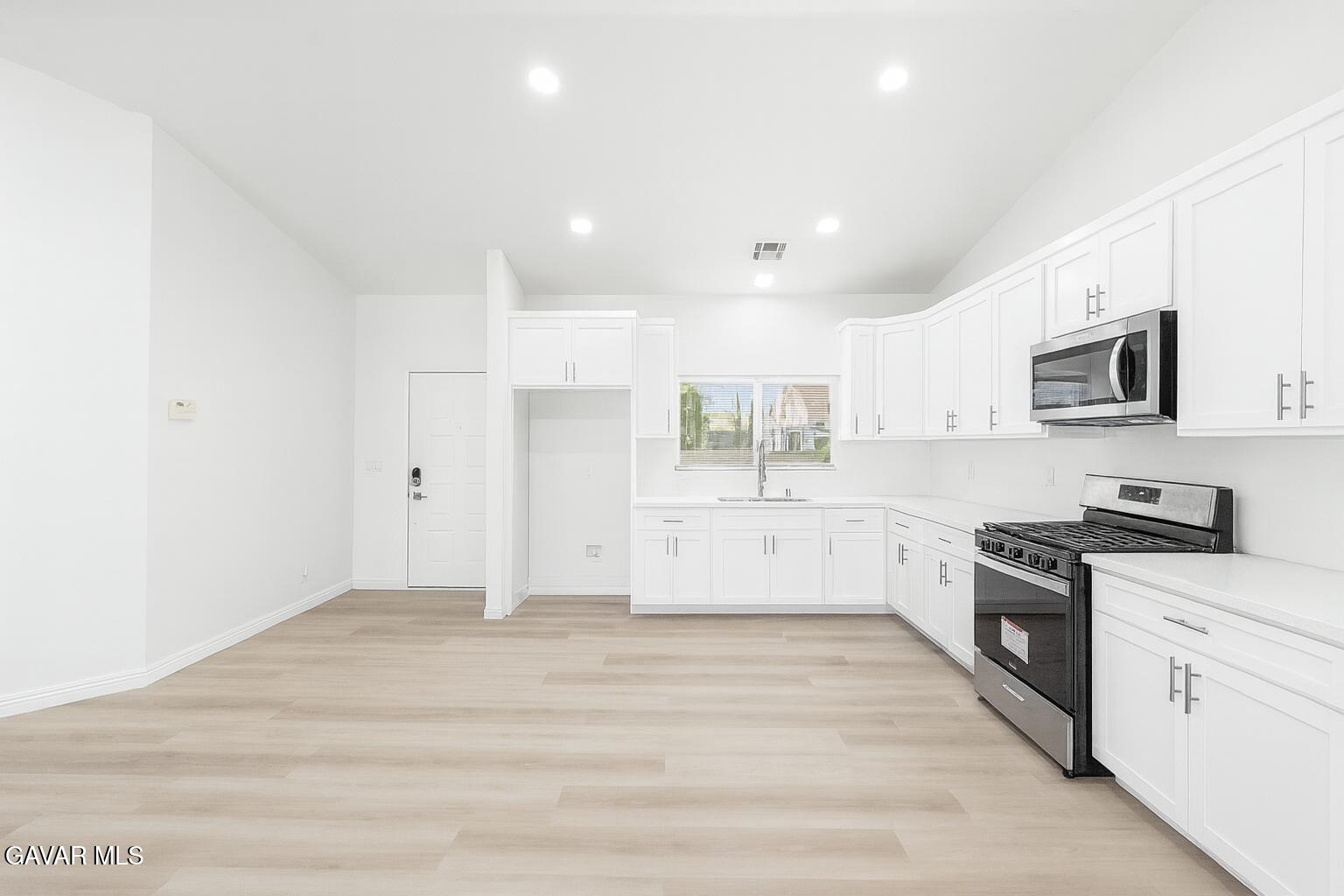44238 Encanto Way Lancaster, CA 93536 - Photo 5 of 32 a large white kitchen with granite countertop a stove top oven a sink a counter space and cabinets
