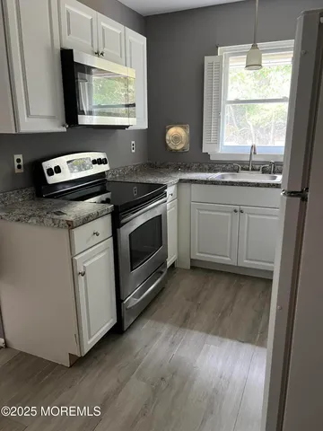 a kitchen with granite countertop wooden cabinets appliances and a window