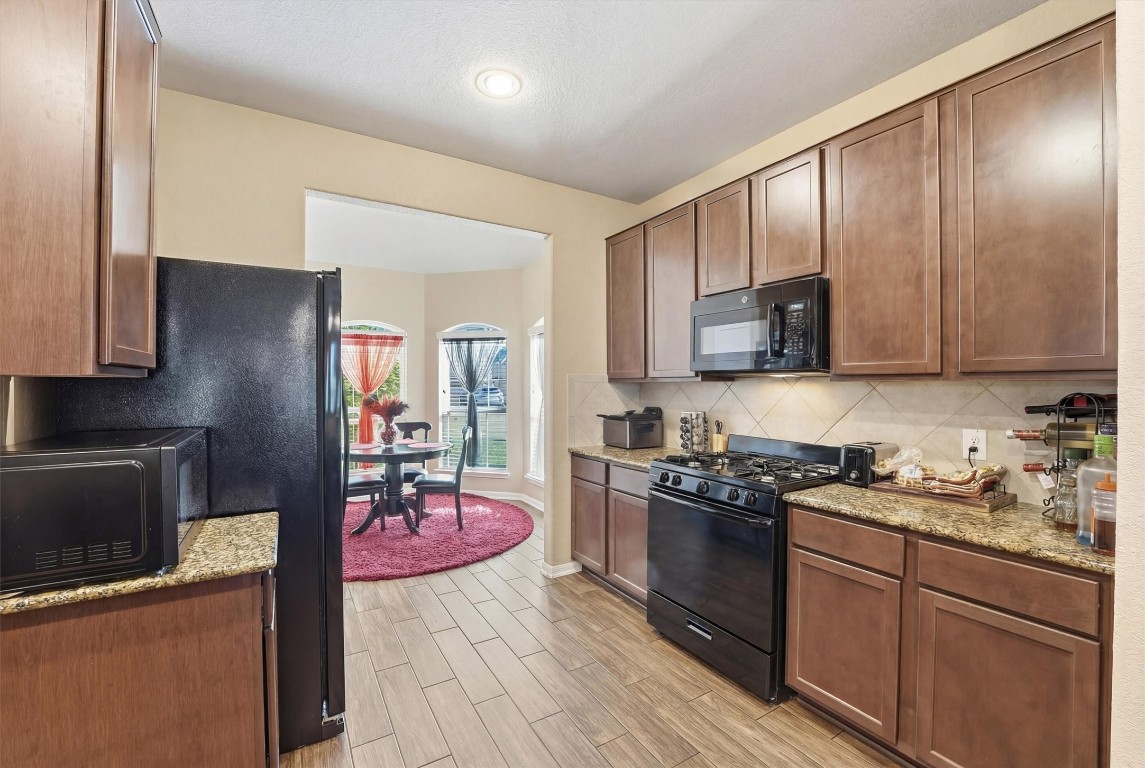 14706 Ruddy Duck Lane Houston, TX 77049 - Photo 10 of 32 a kitchen with stainless steel appliances granite countertop a stove top oven a sink dishwasher a refrigerator and cabinets with wooden floor