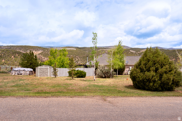 7343 North Sawtooth Cv Road Vernal, UT 84078 - Photo 58 of 64 Expansive property featuring a detached storage shed, mature evergreen shrubs, various deciduous trees, and a wooden privacy fence