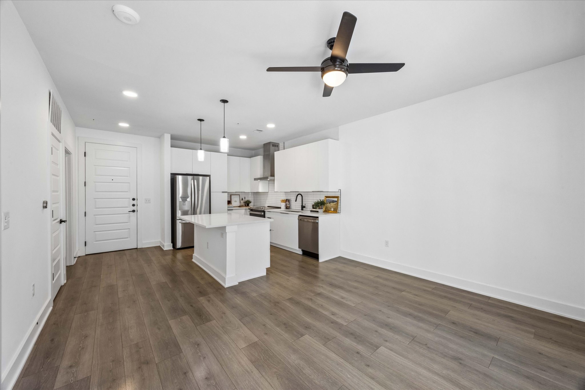 2220 Webberville Road, Unit 216 Austin, TX 78702 - Photo 5 of 26 Open-concept living area featuring wood-finish flooring, a contemporary kitchen with a center island, stainless steel appliances, white cabinetry, and recessed lighting
