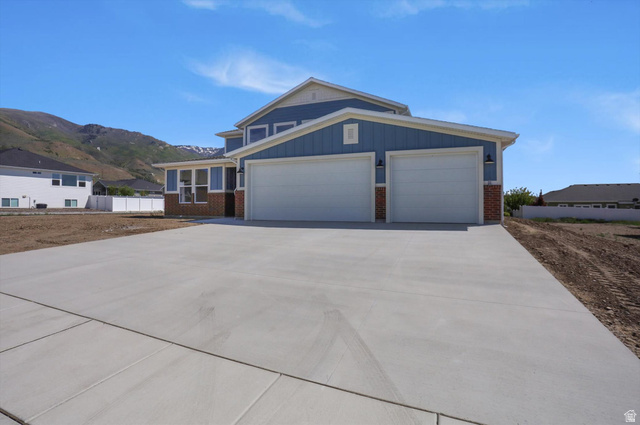 1315 West 3200 South, Unit 17 Perry, UT 84302 - Photo 57 of 58 Contemporary home exterior featuring blue siding, red brick accents, and a wide concrete driveway