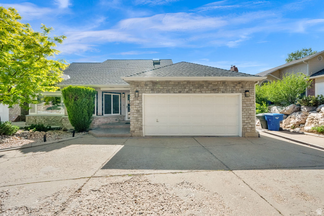 5057 South Ridgedale Drive Ogden, UT 84403 - Photo 4 of 69 Stone façade residence featuring an attached two-car garage, dark shingle roof, and expansive driveway