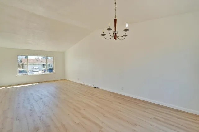 a kitchen with stainless steel appliances granite countertop a refrigerator a sink and white cabinets with wooden floor