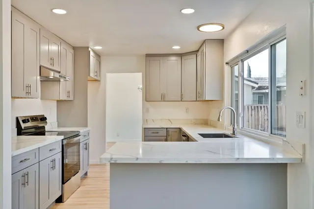 a kitchen with stainless steel appliances granite countertop a sink a stove and a refrigerator