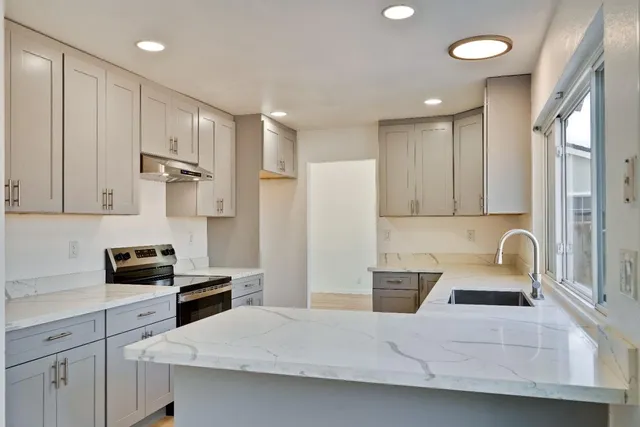 a kitchen with granite countertop white cabinets and a wooden floor