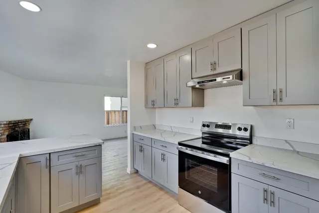 an empty room with wooden floor fireplace and windows