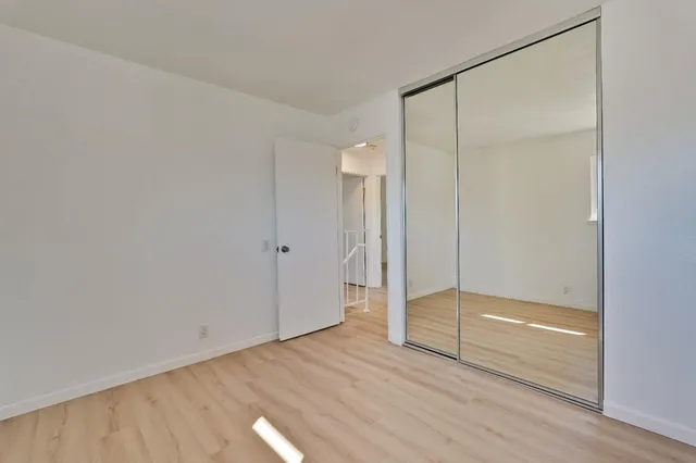 an empty room with wooden floor cabinet and windows