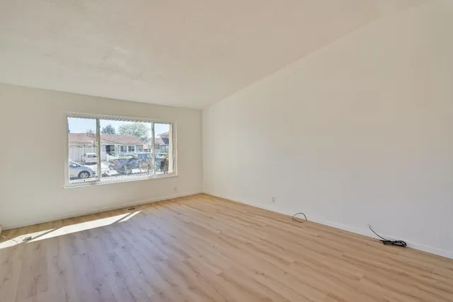 an empty room with wooden floor and window