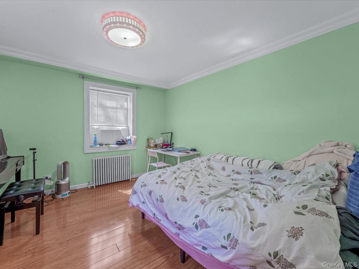 147-11 79th Avenue, Unit 1N Queens, NY 11367 - Photo 6 of 8 Bedroom with wood finished floors, radiator heating unit, and crown molding