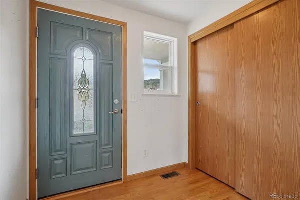 a view of an empty room with wooden floor and closet