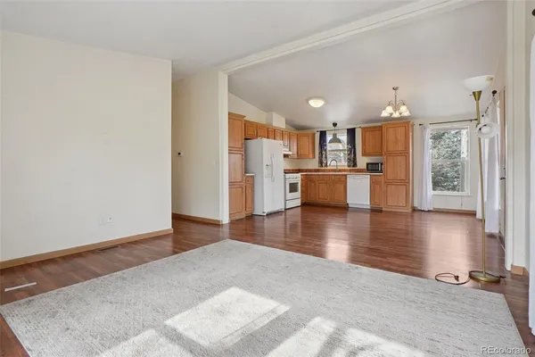 a view of kitchen with stainless steel appliances granite countertop a stove top oven a refrigerator with wooden floors and cabinets