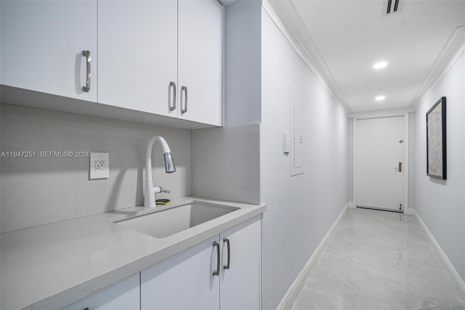 9559 Collins Avenue, Unit S4E Surfside, FL 33154 - Photo 27 of 37 a kitchen with white cabinets and a sink
