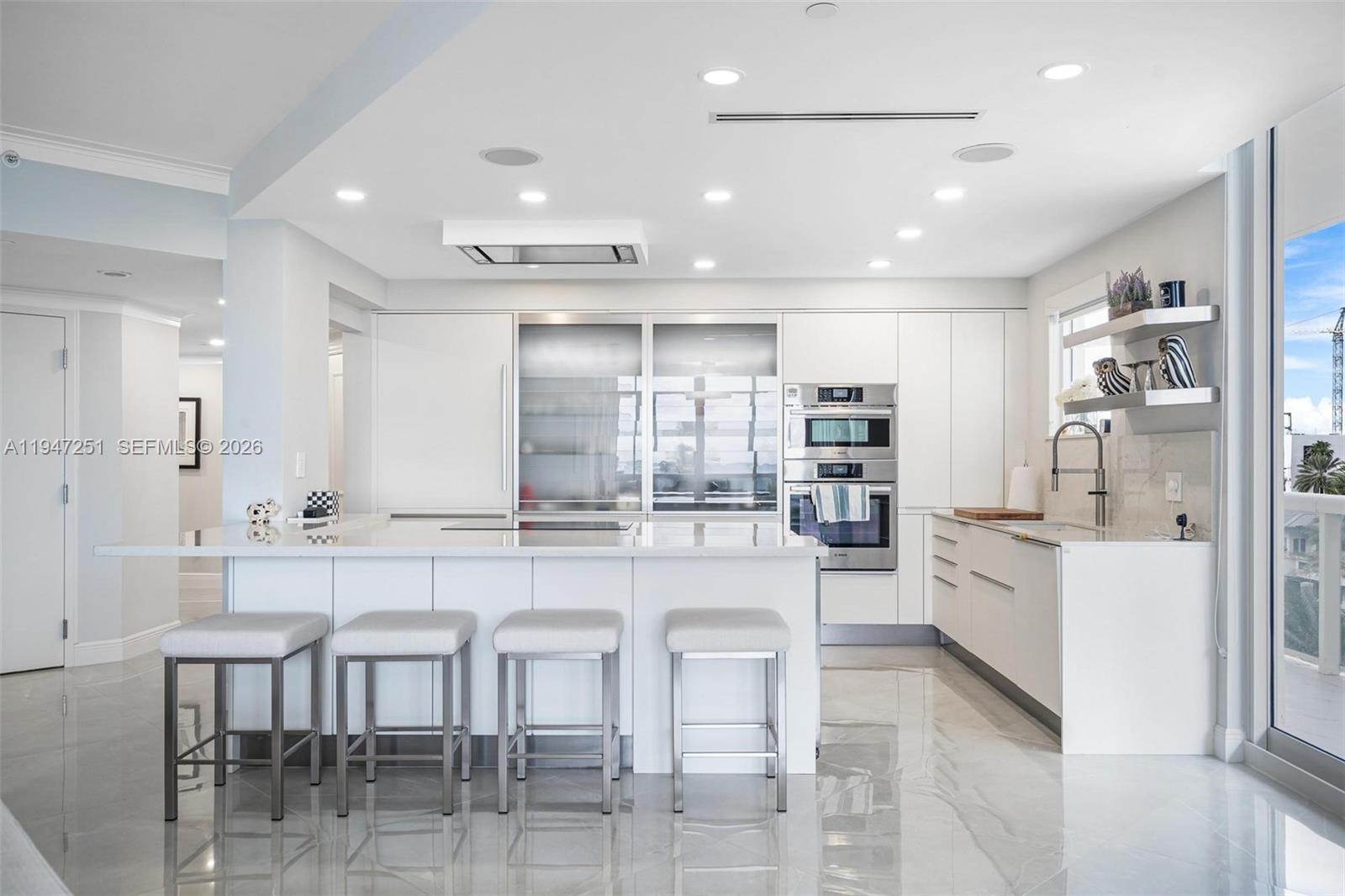 9559 Collins Avenue, Unit S4E Surfside, FL 33154 - Photo 10 of 37 a kitchen with stainless steel appliances kitchen island granite countertop a table and chairs