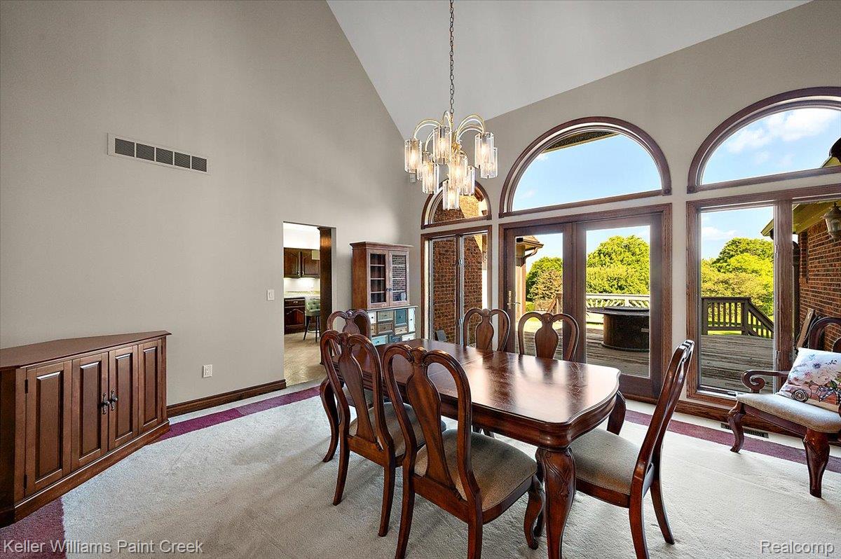 69069 Campground Road Romeo, MI 48065 - Photo 27 of 78 Vaulted ceiling dining area featuring expansive arched windows, glass panel doors, and a decorative chandelier