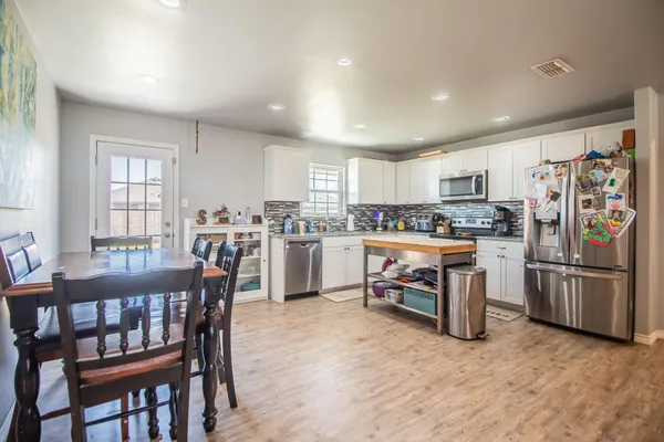 a kitchen with a dining table chairs refrigerator and cabinets