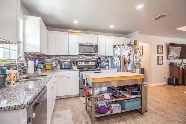 a kitchen with stainless steel appliances granite countertop a stove top oven a sink dishwasher and cabinets with wooden floor