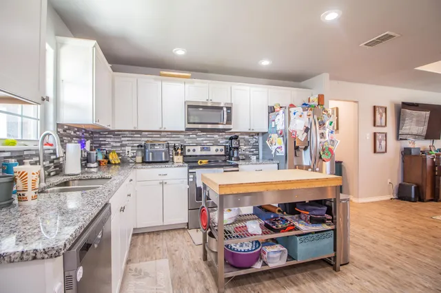 a kitchen with stainless steel appliances granite countertop a stove top oven a sink dishwasher and cabinets with wooden floor