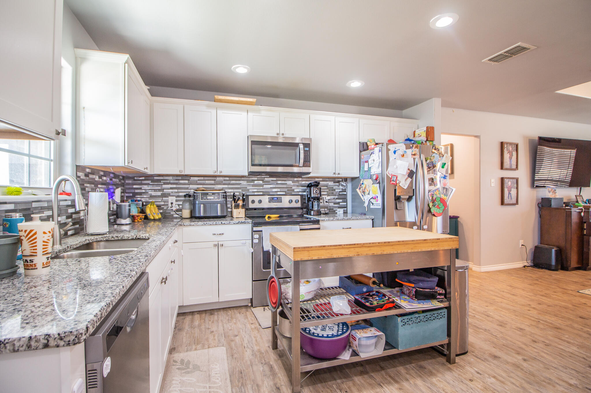 8805 15th Street Lubbock, TX 79416 - Photo 9 of 20 a kitchen with stainless steel appliances granite countertop a stove top oven a sink dishwasher and cabinets with wooden floor