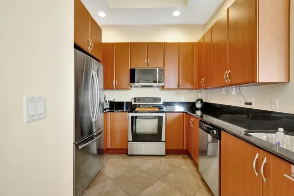 a kitchen with stainless steel appliances granite countertop a table chairs and a refrigerator