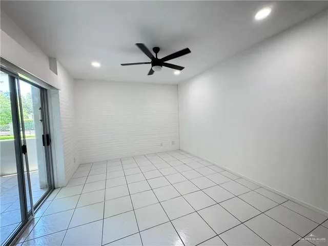 an empty room with windows and ceiling fan