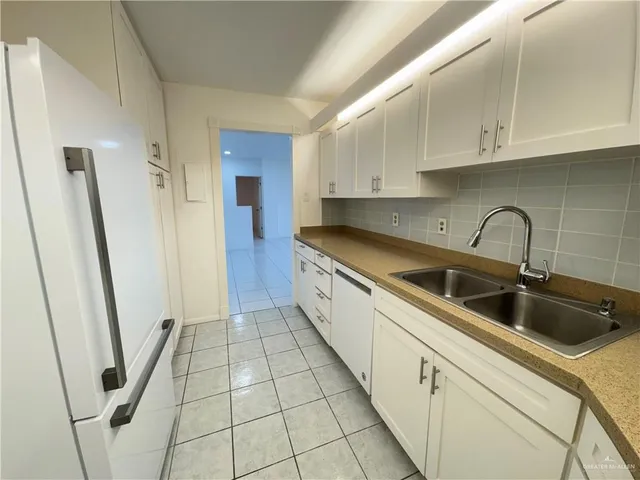 a kitchen with sink a refrigerator and cabinets