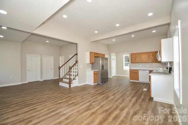 a view of a big room with wooden floor and a kitchen