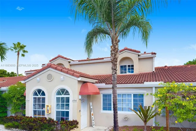 a view of a white house with large windows and a palm tree