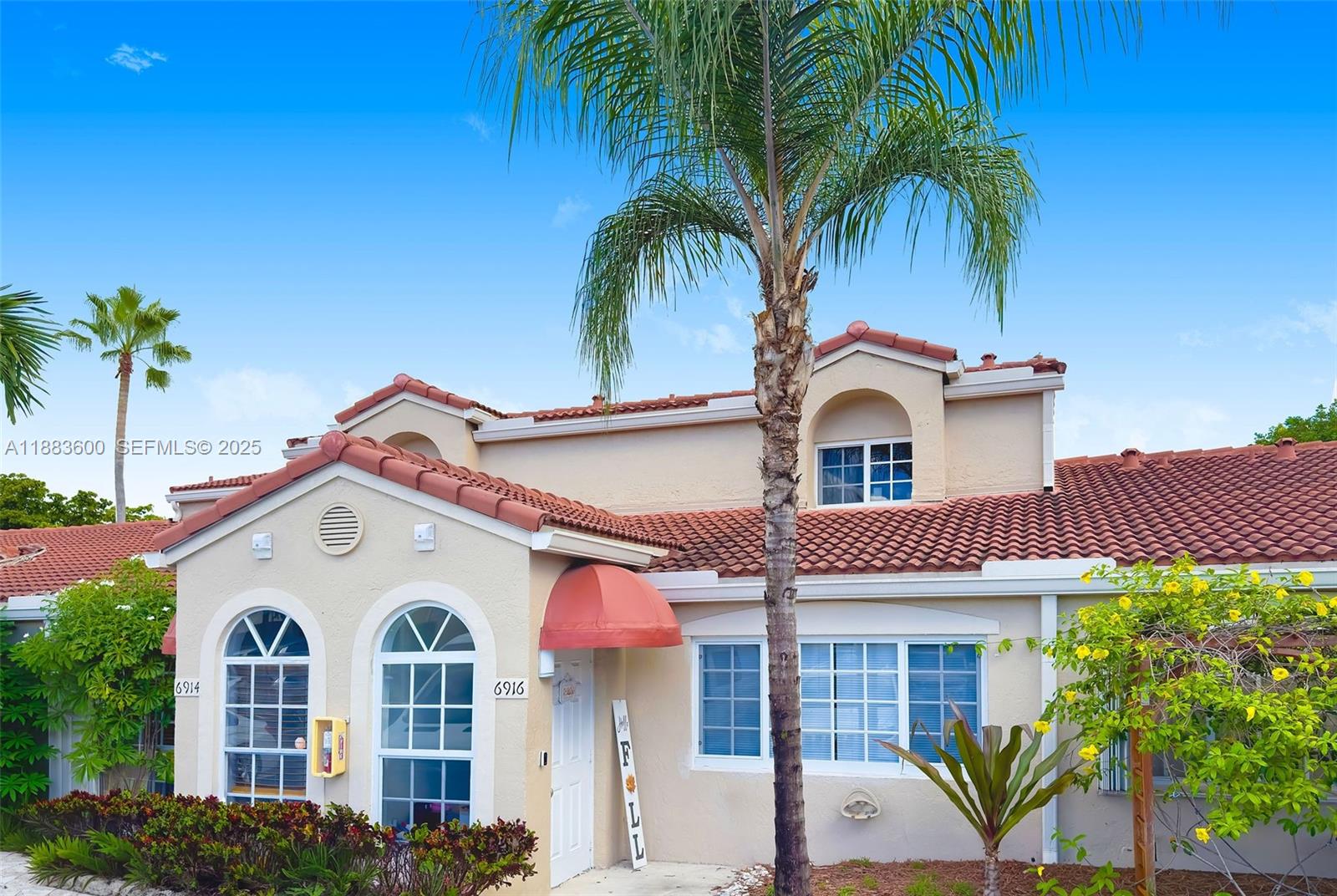 a view of a white house with large windows and a palm tree