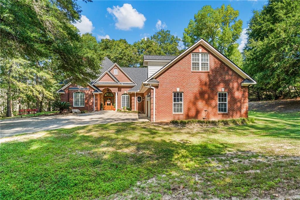 642 Nuckols Road Seale, AL 36875 - Photo 1 of 48 Brick exterior with a gabled roofline, multiple window styles, mature tree coverage, and an expansive front lawn
