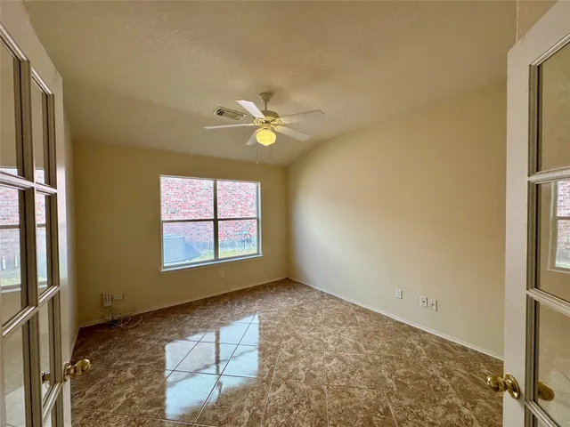 an empty room with windows and ceiling fan