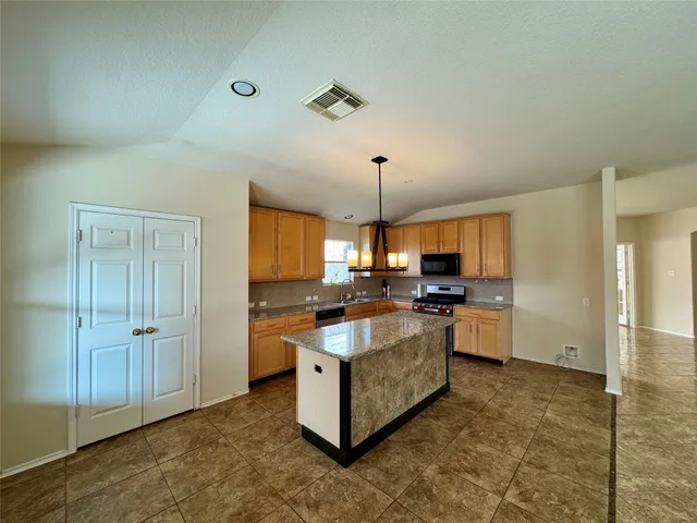 a kitchen with kitchen island granite countertop a stove refrigerator and a sink