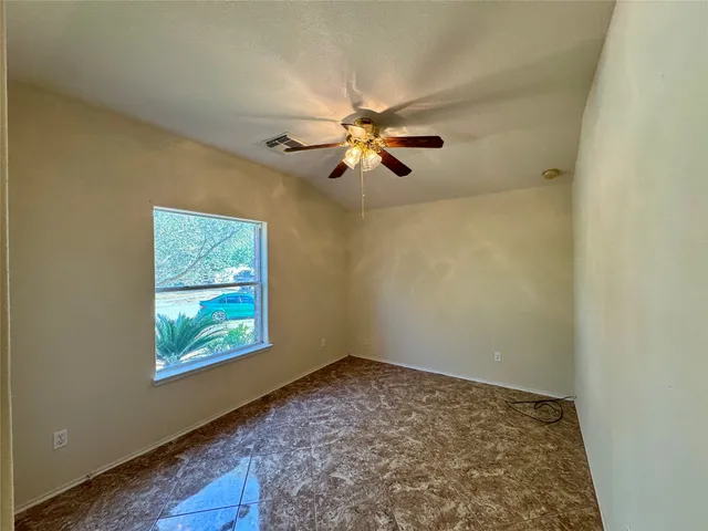 an empty room with windows and fan
