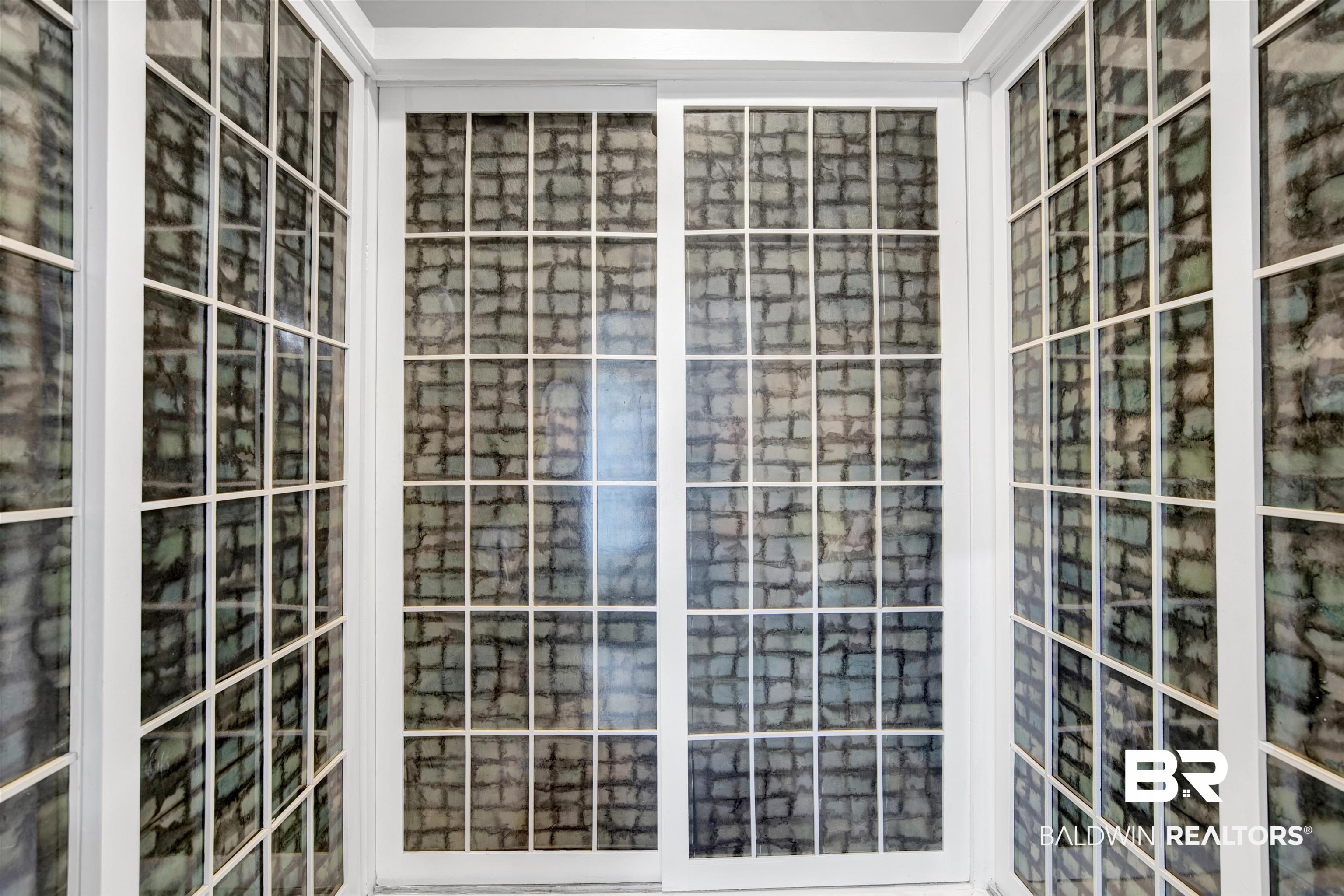 809 Bernard Circle Mobile, AL 36693 - Photo 39 of 75 White framed sliding glass doors with grid patterns, flanked by matching fixed pane windows