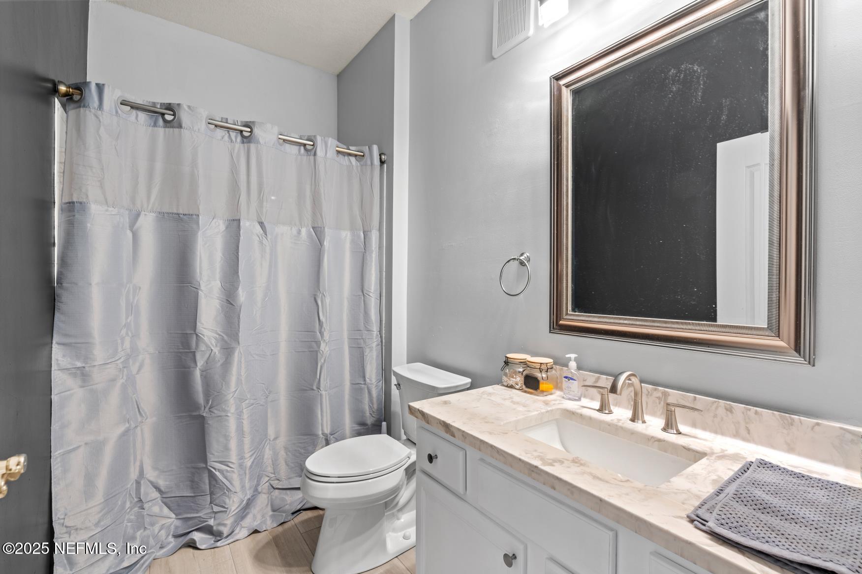 8601 Beach Boulevard, Unit 905 Jacksonville, FL 32216 - Photo 19 of 27 a bathroom with a granite countertop sink toilet and shower