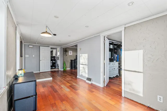 a view of a hallway with wooden floor and a cabinet