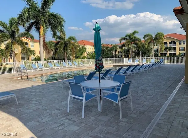 a view of a swimming pool with a lawn chairs and palm tree