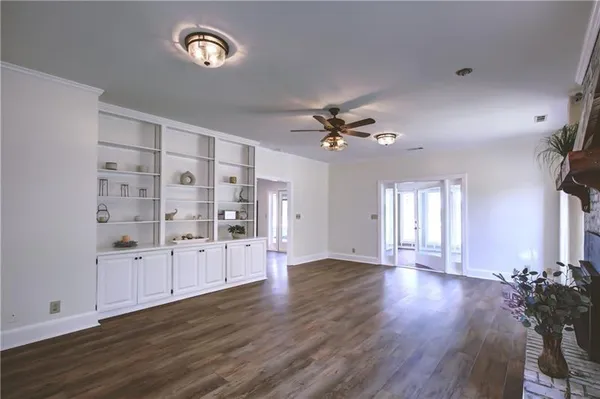 a view of an empty room with wooden floor and window