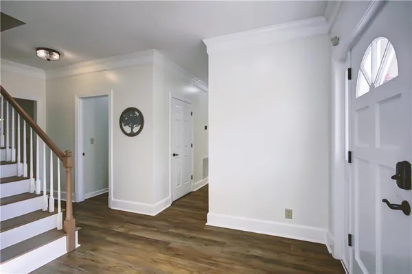 an empty room with wooden floor chandelier and windows