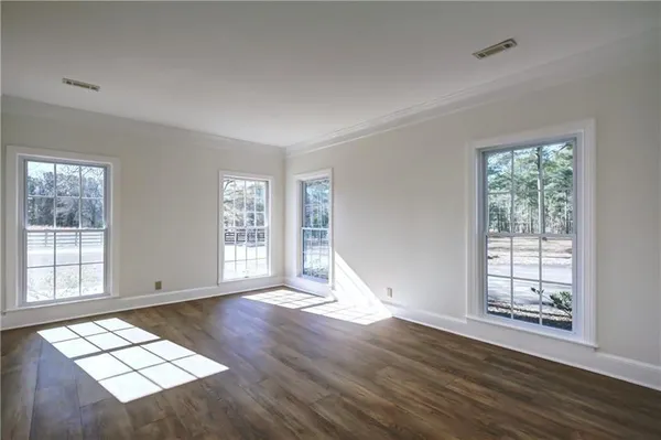 a view of empty room with wooden floor and window