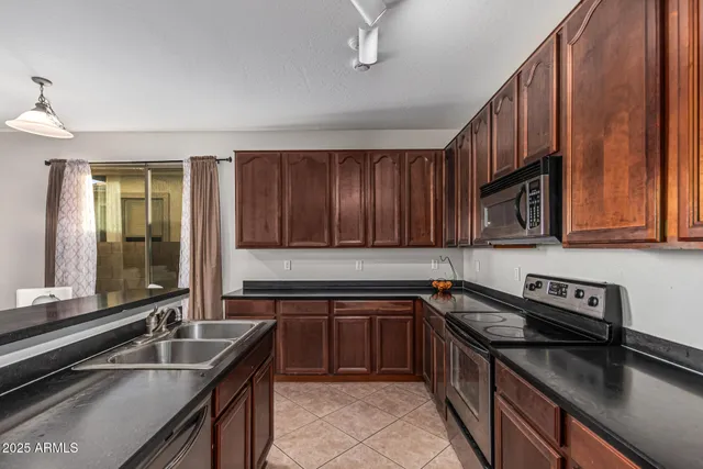 a kitchen with granite countertop stainless steel appliances a sink stove and cabinets