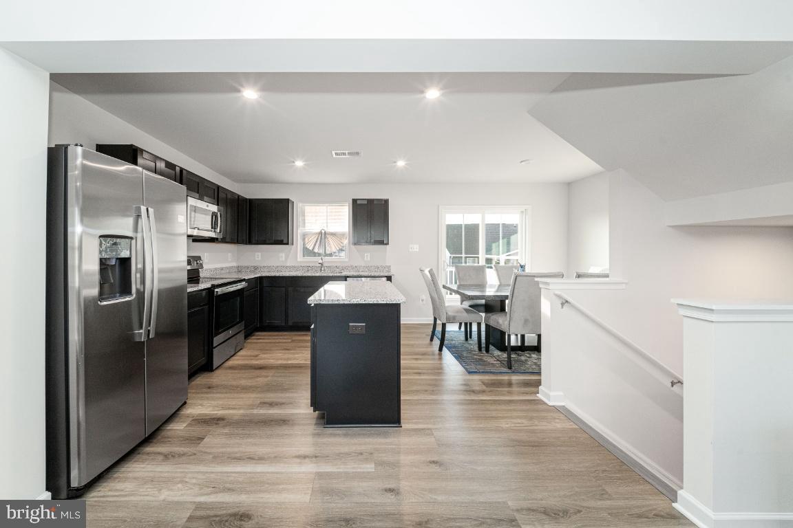 18256 Capital Court Ruther Glen, VA 22546 - Photo 13 of 26 a kitchen with stainless steel appliances granite countertop a refrigerator a sink dishwasher and white cabinets with wooden floor