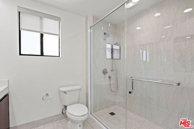 a bathroom with a granite countertop toilet a sink and shower