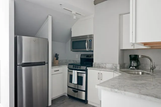 a kitchen with a refrigerator sink and white cabinets