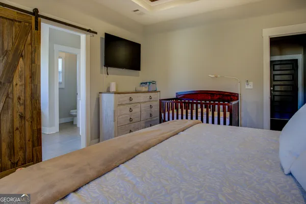 a bedroom with a bed and a flat tv screen on dresser